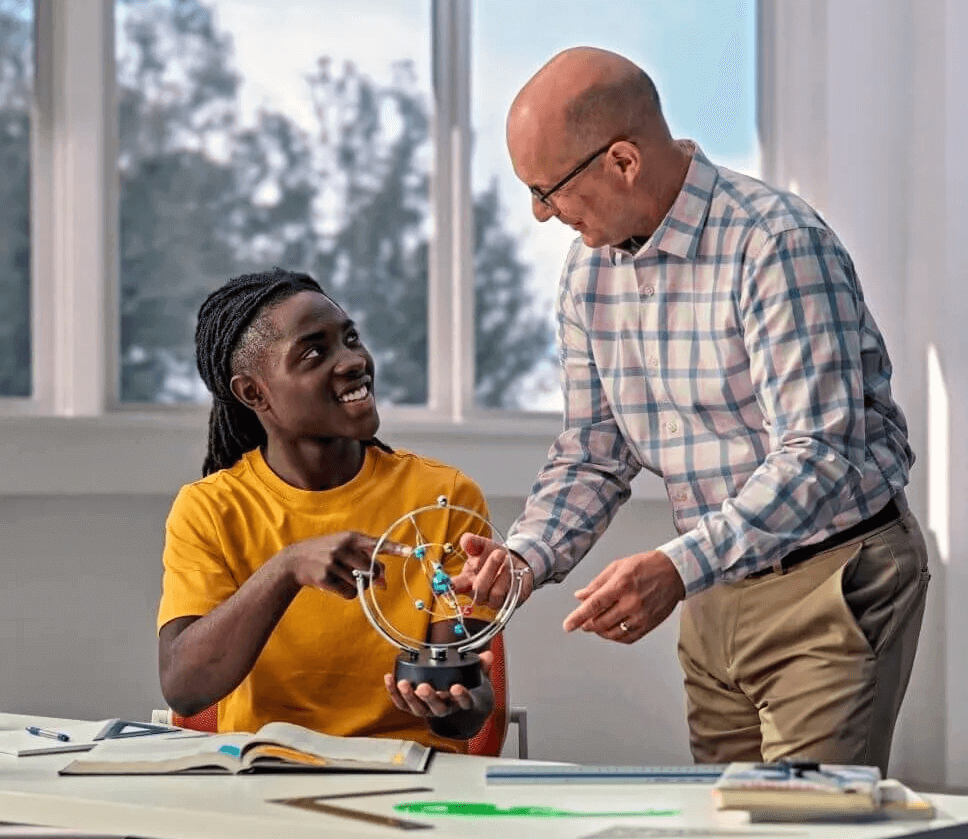 Student studying with teacher in classroom
